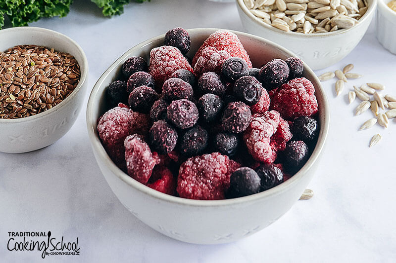 bowls of ingredients: flax seeds, sunflower seeds, and frozen mixed berries