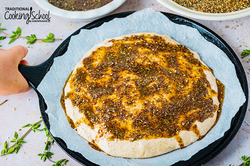 Manakish spread with olive oil and za'atar mix ready to bake.