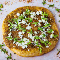 manakish (Middle Eastern pizza) topped with labneh cheese, za'atar seasoning and herbs