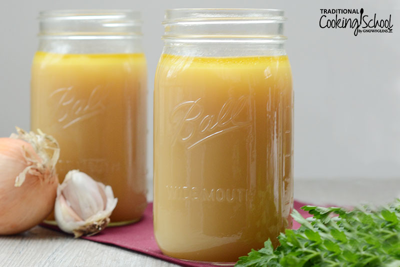 two glass quart-sized Mason jars of golden-colored beef stock