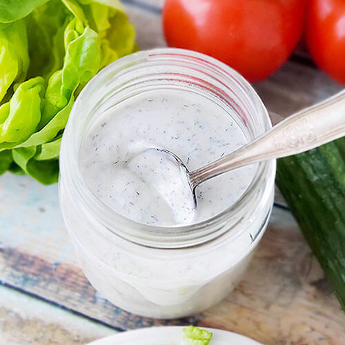 spoon scooped into a creamy white herbed salad dressing