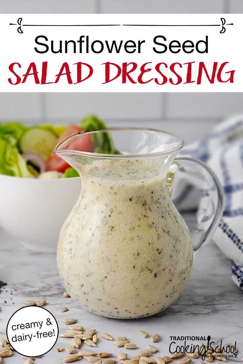 glass pitcher of light-colored dressing with black specks, with a green salad in the background and text overlay: "Sunflower Seed Salad Dressing (creamy & dairy-free!)"