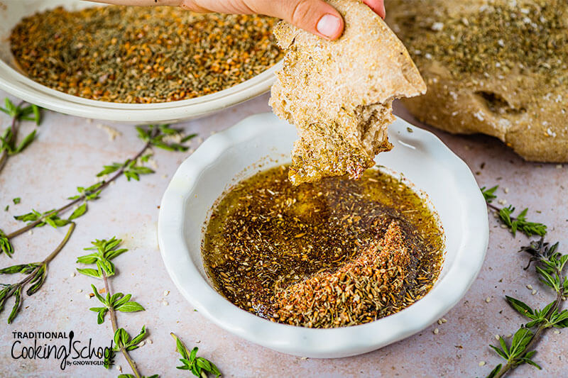 Flatbread being dipped into a bowl of olive oil and Za'atar seasoning.