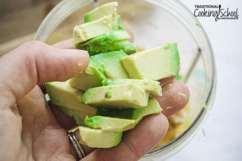 woman's hand holding up chunks of avocado