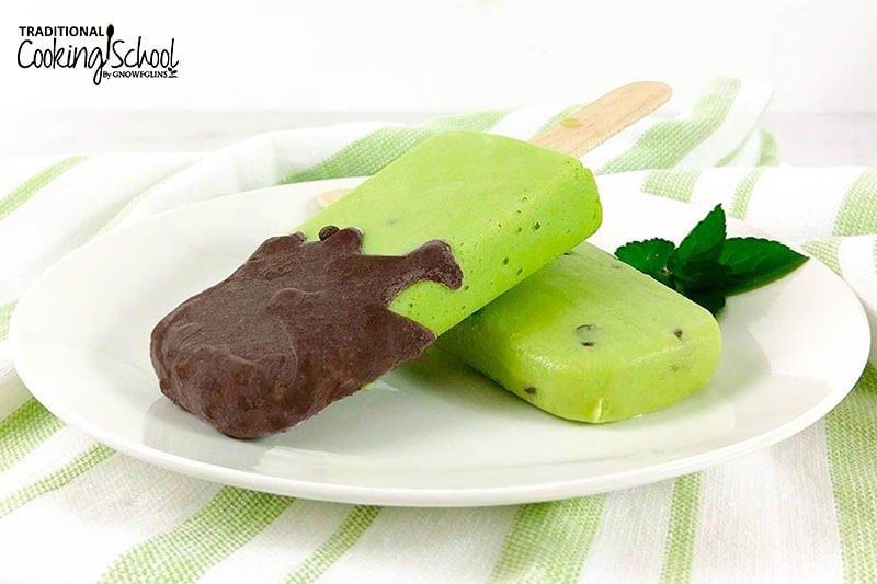 two popsicles, one dipped in chocolate, on a plate