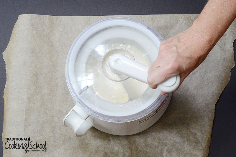 woman's hand churning a hand crank ice cream maker