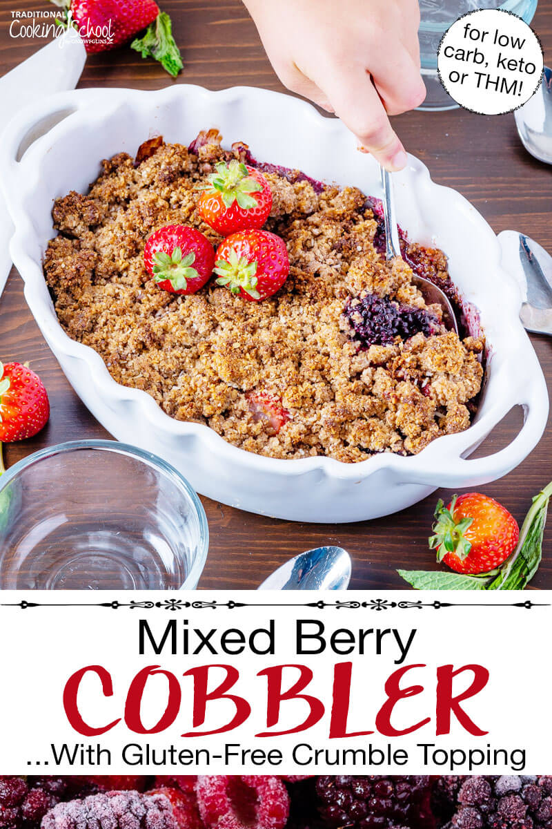 Scooping into a cobbler garnished with fresh strawberries, in a white casserole dish with scalloped edges. Text overlay says: "Mixed Berry Cobbler ...With Gluten-Free Crumble Topping (for low carb, keto, or THM!)"