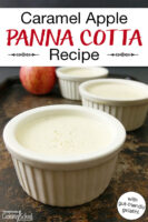 Panna cotta in small ceramic bowls on a tray with an apple in the background. Text overlay says: "Caramel Apple Panna Cotta Recipe (with gut-friendly gelatin!)"