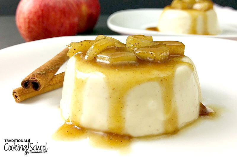 Panna cotta on a plate topped with sauteed apple chunks and a caramel sauce.