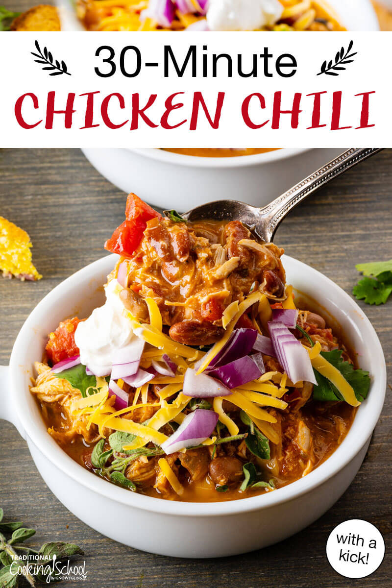 Bowl of chili topped with sour cream, red onion, cilantro, and grated cheddar cheese, and a ladle spooning more chili over top. Text overlay says: "30-Minute Chicken Chili (with a kick!)"