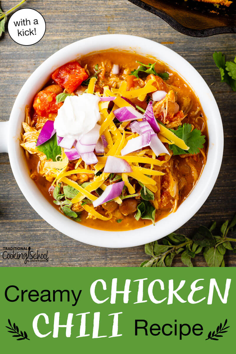 A bowl of chili topped with sour cream, red onion, cilantro, and grated cheddar cheese. Text overlay says: "Creamy Chicken Chili Recipe (with a kick!)"