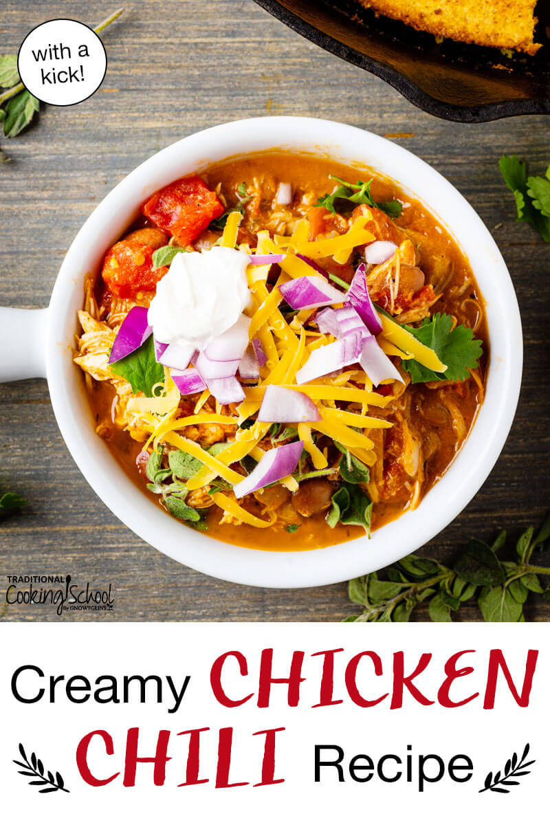 A bowl of chili topped with sour cream, red onion, cilantro, and grated cheddar cheese. Text overlay says: "Creamy Chicken Chili Recipe (with a kick!)"