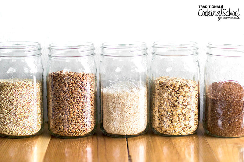 Row of jars filled with grains: quinoa, spelt, rice, rolled oats, and teff.