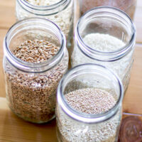 Jars of whole grains, includin quinoa, spelt, and rice.