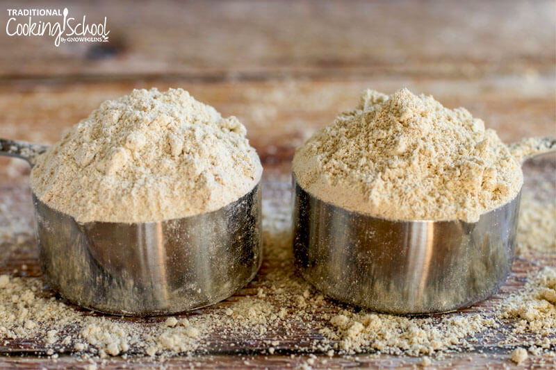 Two stainless steel measuring cups full of flour.
