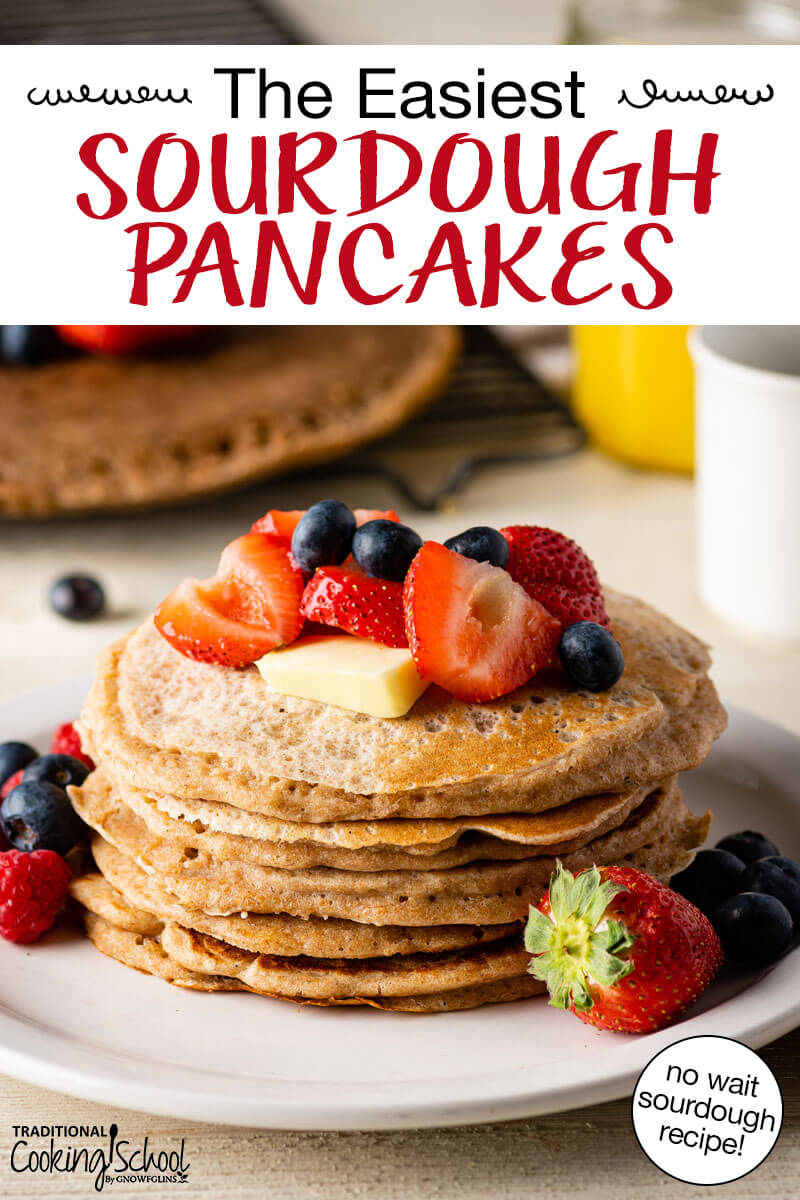 Stack of sourdough pancakes on a plate topped with fresh fruit and butter. Text overlay says: "The Easiest Sourdough Pancakes (no wait sourdough recipe!)"