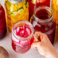 Holding up a glass jar of beet kvass with ice cubes.