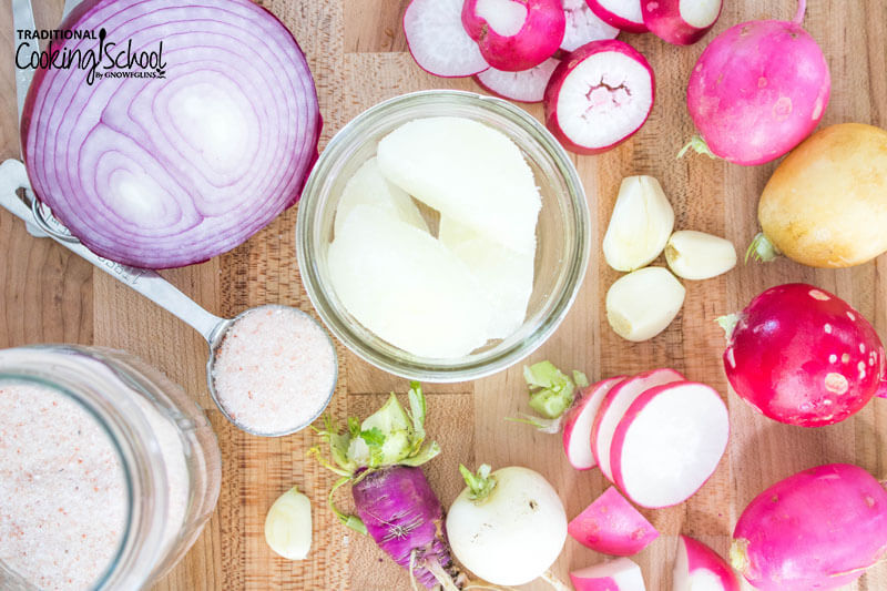Ingredients for fermenting radishes: red onion, salt, garlic gloves, radishes.