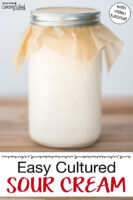 Jar of cream covered with parchment paper and a metal band. Text overlay says: "Easy Cultured Sour Cream (with video tutorial)"