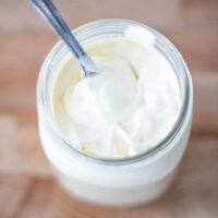Thickened homemade sour cream in a glass jar.