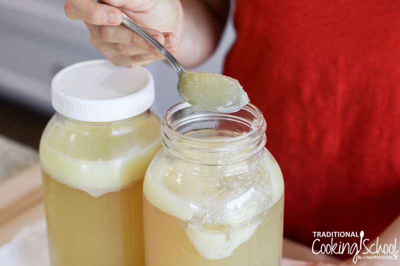 Woman scooping out a spoonful of homemade broth from a jar. Homemade "gelled" broth is rich in gelatin with many health benefits, including boosting gut health and strengthening hair, skin, and nails.