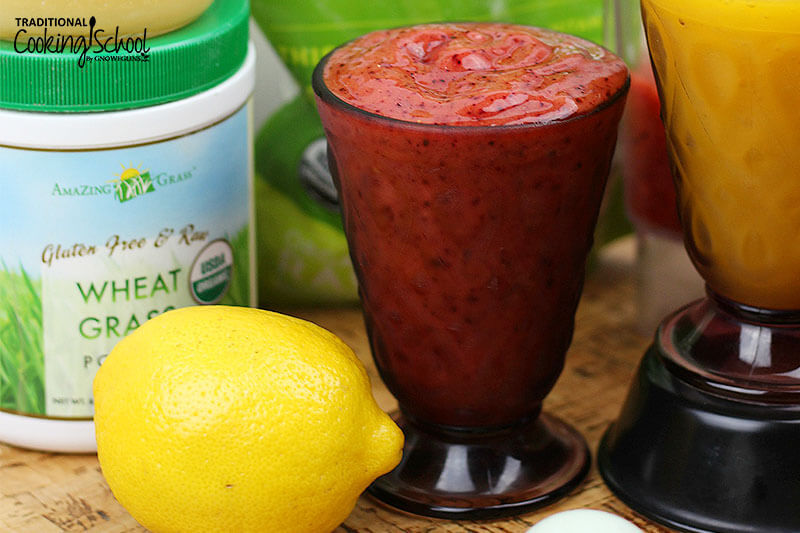 Smoothie in a glass surrounded by healthy ingredients to include in smoothies, such as wheat grass.