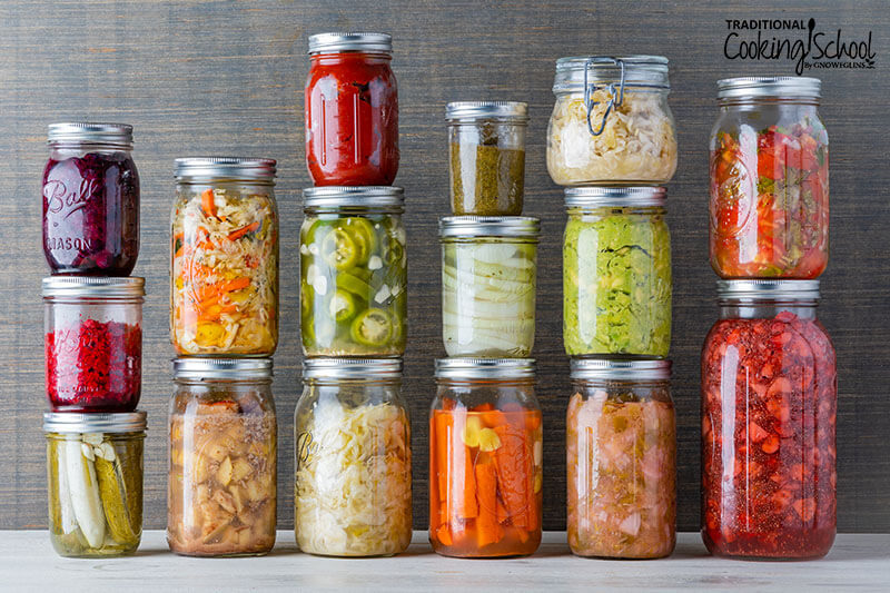 An array of fermented foods in glass jars stacked on top of each other and arranged in a row.