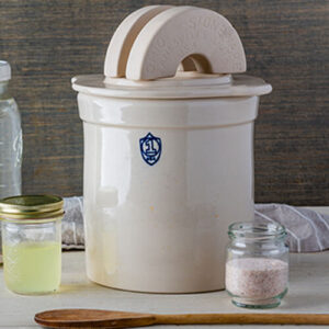 Photo of a stoneware fermenting crock with lid and weights.