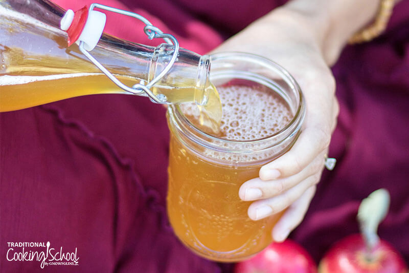 Pouring fizzy, fermented apple cider into a glass jar.