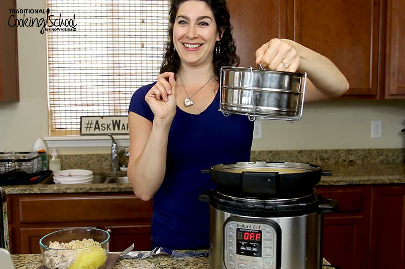 A smiling woman holding up two pots stacked on top of each other, with her Instant Pot on the counter next to her.