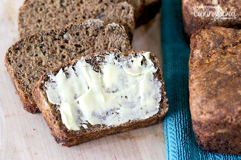 Slices of homemade banana bread. The foremost slice is generously buttered.
