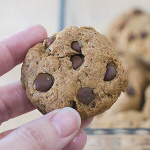 Woman's hand holding up a chocolate chip cookie.